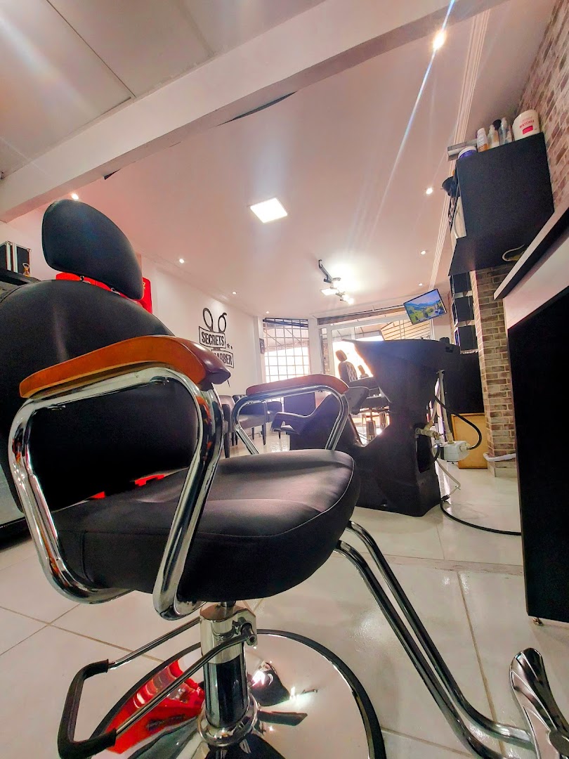 Interior amplo da Secrets Barber com cadeiras de barbeiro e balcão de atendimento