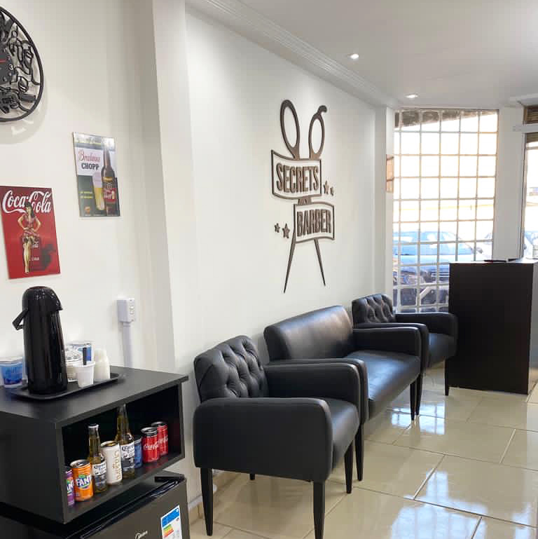 Área de espera da Secrets Barber com poltronas e frigobar de bebidas